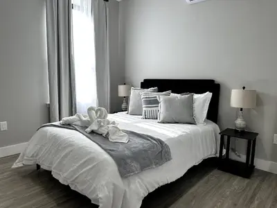 a white bedroom with a large bed with a teddy bear on it at Spacious Modern 1 Bedroom RARE Apt w GYM in Albany