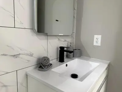 a white bathroom with a sink and a mirror at Spacious Modern 1 Bedroom RARE Apt w GYM in Albany