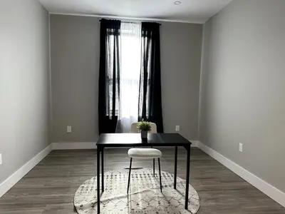 a table and a chair in a room with a window at Spacious Modern 1 Bedroom RARE Apt w GYM in Albany