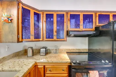 a kitchen with wooden cabinets and a stove top oven at A-Frame Retreat Next to Grafton Lakes St Park