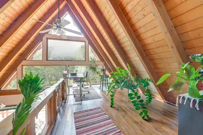 a room with a vaulted ceiling with windows and plants at A-Frame Retreat Next to Grafton Lakes St Park