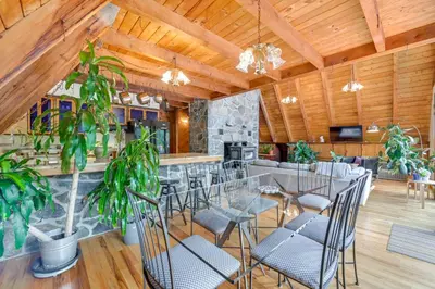 a dining room with tables and chairs and a stone bar at A-Frame Retreat Next to Grafton Lakes St Park