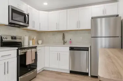 a kitchen with white cabinets and a stainless steel refrigerator at Westville Nest parking NearYale Newly Renovated in New Haven
