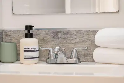 a bathroom sink with a bottle of hand soap next to a faucet at Westville Nest parking NearYale Newly Renovated in New Haven