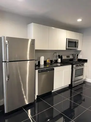 a kitchen with a stainless steel refrigerator and white cabinets at MODERN 1BR Apt with PRIVATE deck in Albany