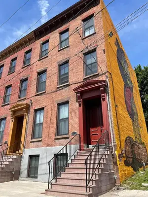 a large brick building with a red door and stairs at MODERN 1BR GREAT Location Downtown Parking in Albany