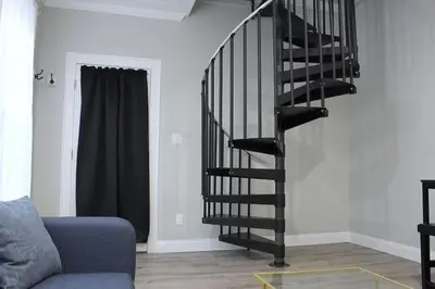 a black spiral staircase in a living room with a couch at UNIQUE Gem in HEART of Albany Spiral Staircase in Albany