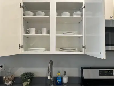 a kitchen counter with white cabinets with dishes in it at Bright & Airy 1 BDRM Private Apt in Albany