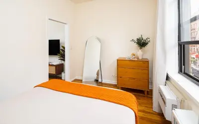 a bedroom with a bed and a dresser and a mirror at Cozy 1BD Upper East Side Gem in New York