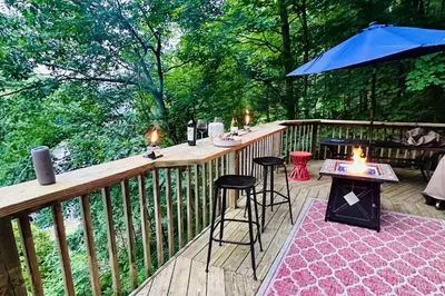 a deck with a bar with a table and chairs at Lake Zoar Cabin in Newtown