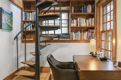 a room with a desk and a spiral book shelf at Lake Zoar Cabin in Newtown