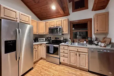 a kitchen with stainless steel appliances and wooden cabinets at Lake Zoar Cabin in Newtown