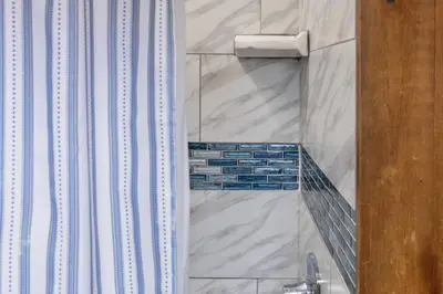 a shower with blue and white tile in a bathroom at Lake Zoar Cabin in Newtown