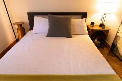 a bed with white sheets and pillows in a room at Lake Zoar Cabin in Newtown