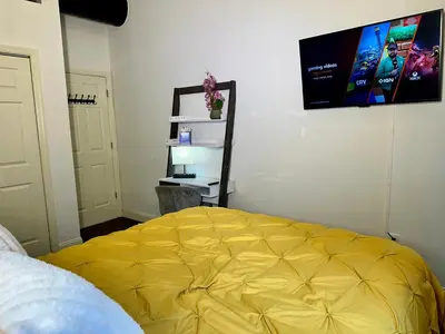 a bedroom with a yellow bed and a tv on the wall at BP STAYS - Hotel-Style, No Host, Professionally Managed ID302 in Jersey City