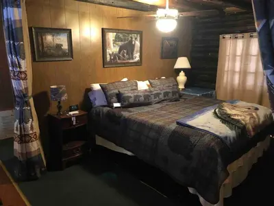 a bedroom with a bed and a table with a lamp at Unique and charming, exquisitely themed Log Cabin in Arietta