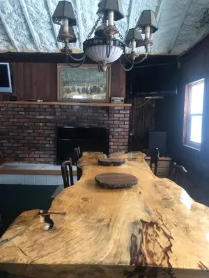 a large wooden table in a room with a fireplace at Unique and charming, exquisitely themed Log Cabin in Arietta