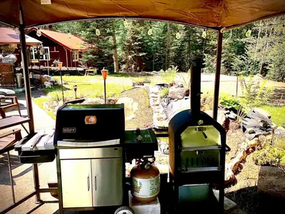 a grill and smoker under a tent in a yard at Unique and charming, exquisitely themed Log Cabin in Arietta
