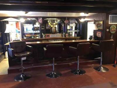 a bar with chairs and a counter in a room at Unique and charming, exquisitely themed Log Cabin in Arietta