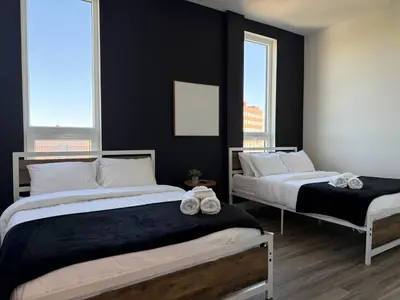 two beds in a bedroom with black walls and windows at NYC View, Free Parking, 2bath in East Orange