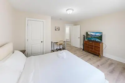 a bedroom with a white bed and a flat screen tv at Downtown Haven Walk to Yale Renovated Parking in New Haven