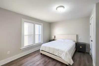 a white bedroom with a bed and two windows at Downtown Haven Walk to Yale Renovated Parking in New Haven