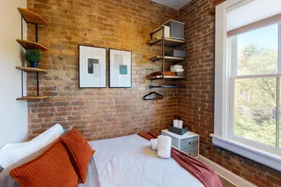 a brick wall in a room with a bed and a window at Bright Downtown Room near Yale & East Rock! in New Haven