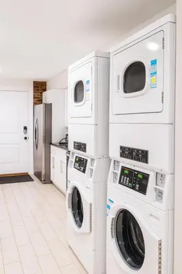 a laundry room with three washer and dryer machines at Bright Downtown Room near Yale & East Rock! in New Haven