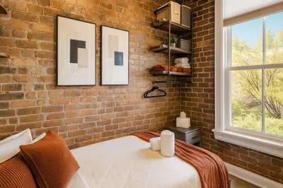 a bedroom with a brick wall and a bed with two mirrors at Bright Downtown Room near Yale & East Rock! in New Haven