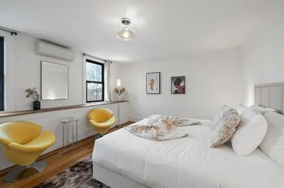 a white bedroom with a bed and a yellow chair at Lakeview-Sleeps 12-King Suites-7BR - Firepit in Monroe