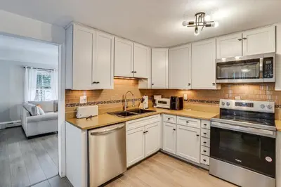 a kitchen with white cabinets and stainless steel appliances at 2 Mi to Town Home with Patio and Yard in Waterbury! in Waterbury