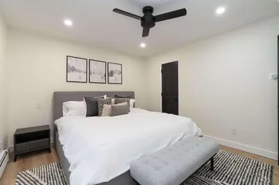 a bedroom with a white bed and a ceiling fan at Modern Catskills Retreat with Creek & Fire Pit in Cairo