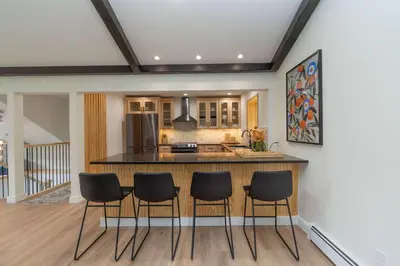 a kitchen with a bar with four chairs around it at Modern Catskills Retreat with Creek & Fire Pit in Cairo