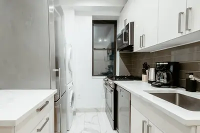 a white kitchen with a sink and a stove at Spacious 3BR Upper West Side Apt - Steps from Central Park in New York