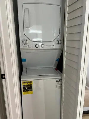 a small white refrigerator with a microwave on top of it at Modern 2BR and Office Near NYC With Parking - Sleeps 6 in Jersey City
