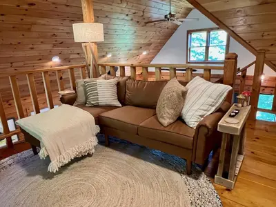a living room with a brown couch in a cabin at Perfect Vermont Battenkill Log Cabin in Arlington