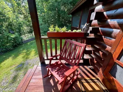 a red bench sitting on the porch of a cabin at Perfect Vermont Battenkill Log Cabin in Arlington