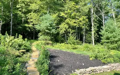 a garden with a gravel path and trees at Perfect Vermont Battenkill Log Cabin in Arlington