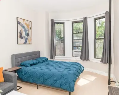 a bedroom with a bed and a couch and windows at Albany Studio with Kitchen, WiFi, Gym and Game Room Near Capitol in Albany