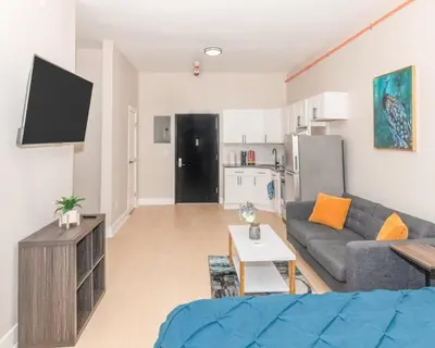 a living room with a couch and a kitchen at Albany Studio with Kitchen, WiFi, Gym and Game Room Near Capitol in Albany