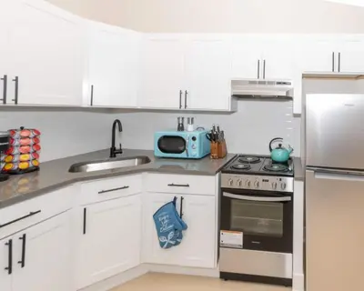 a kitchen with white cabinets and a stove and a microwave at Albany Studio with Kitchen, WiFi, Gym and Game Room Near Capitol in Albany
