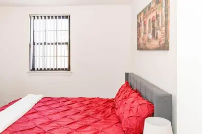 a red bed in a white room with a window at Spacious 1-Bedroom Condo with Kitchen, Free Parking and Fitness Center in Albany