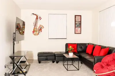 a living room with a black leather couch and red pillows at Spacious 1-Bedroom Condo with Kitchen, Free Parking and Fitness Center in Albany
