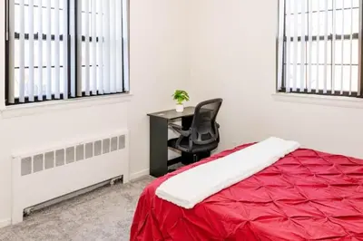 a bedroom with a red bed and a desk with a chair at Spacious 1-Bedroom Condo with Kitchen, Free Parking and Fitness Center in Albany