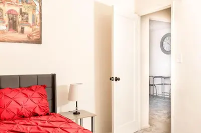 a bedroom with a red bed and a table with a lamp at Spacious 1-Bedroom Condo with Kitchen, Free Parking and Fitness Center in Albany