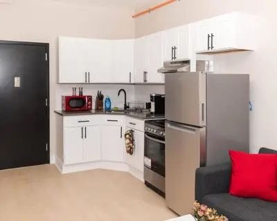 a kitchen with white cabinets and a black refrigerator at Central Albany Apartment Private Unit Near Capitol and Empire Plaza in Albany