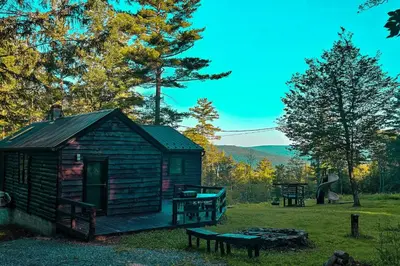 a log cabin in a field with a bench at Views, Pines & Perfect Vibes in Middleburgh