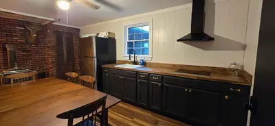 a kitchen with a wooden table and a black refrigerator at Views, Pines & Perfect Vibes in Middleburgh