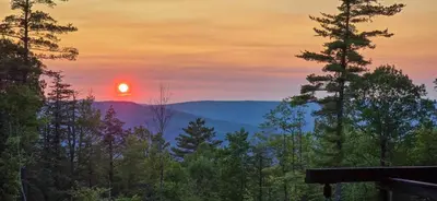 a sunset in the mountains with trees in the foreground at Views, Pines & Perfect Vibes in Middleburgh