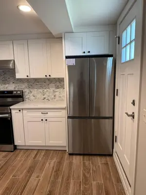 a kitchen with white cabinets and a stainless steel refrigerator at Calm Retreat in Plainview